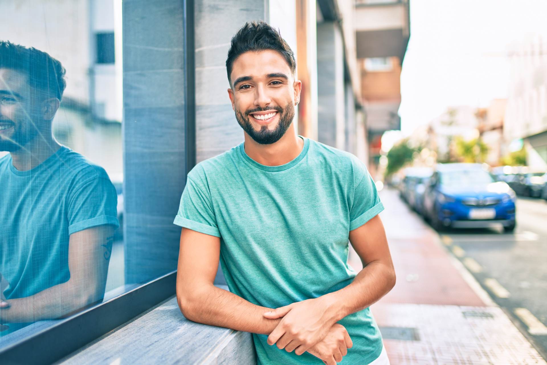 Young arab man smiling happy leaning on the wall at the city.