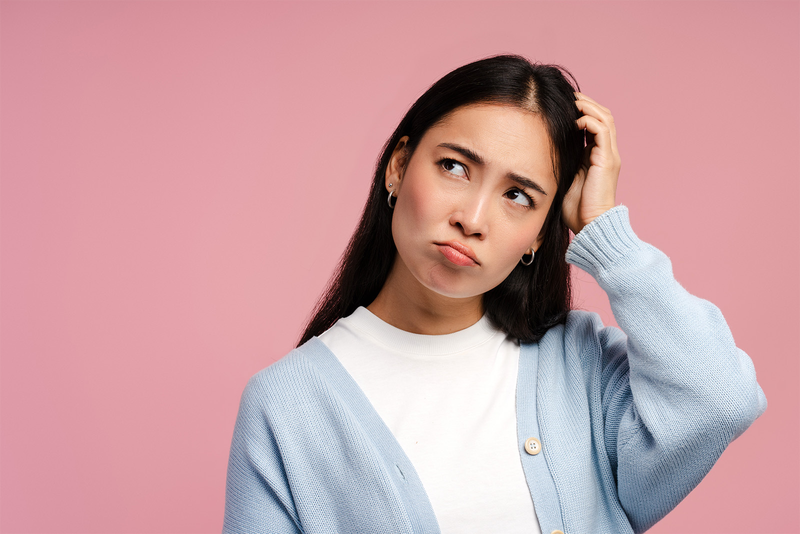 A confused woman scratching her head